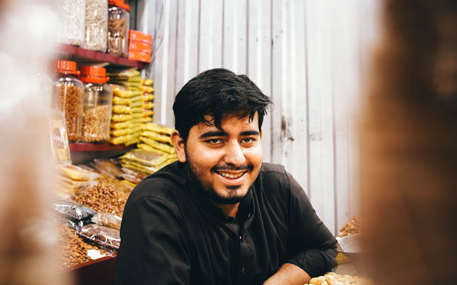 Smiling shopkeeper at a dry-fruit stall in a Karachi market, a typical retail business that needs a POS system
