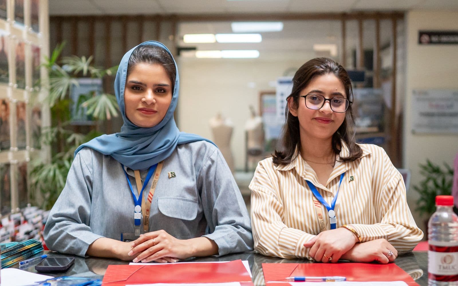 Two Pakistani office professionals smiling at a front desk, the kind of team ERP software supports