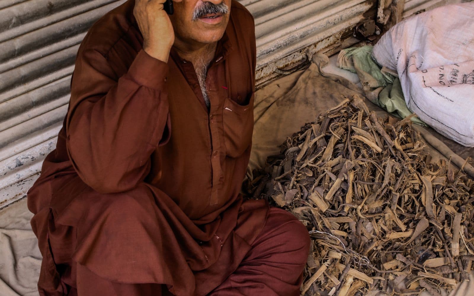 Shopkeeper talking on his mobile phone at his market stall in Hyderabad, Sindh