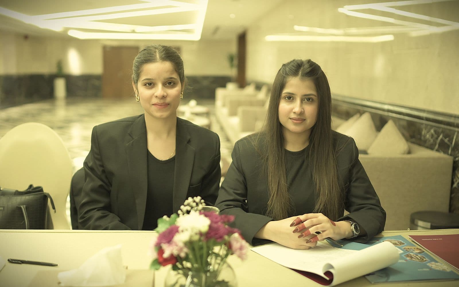Two Pakistani businesswomen seated at a conference table in a modern office