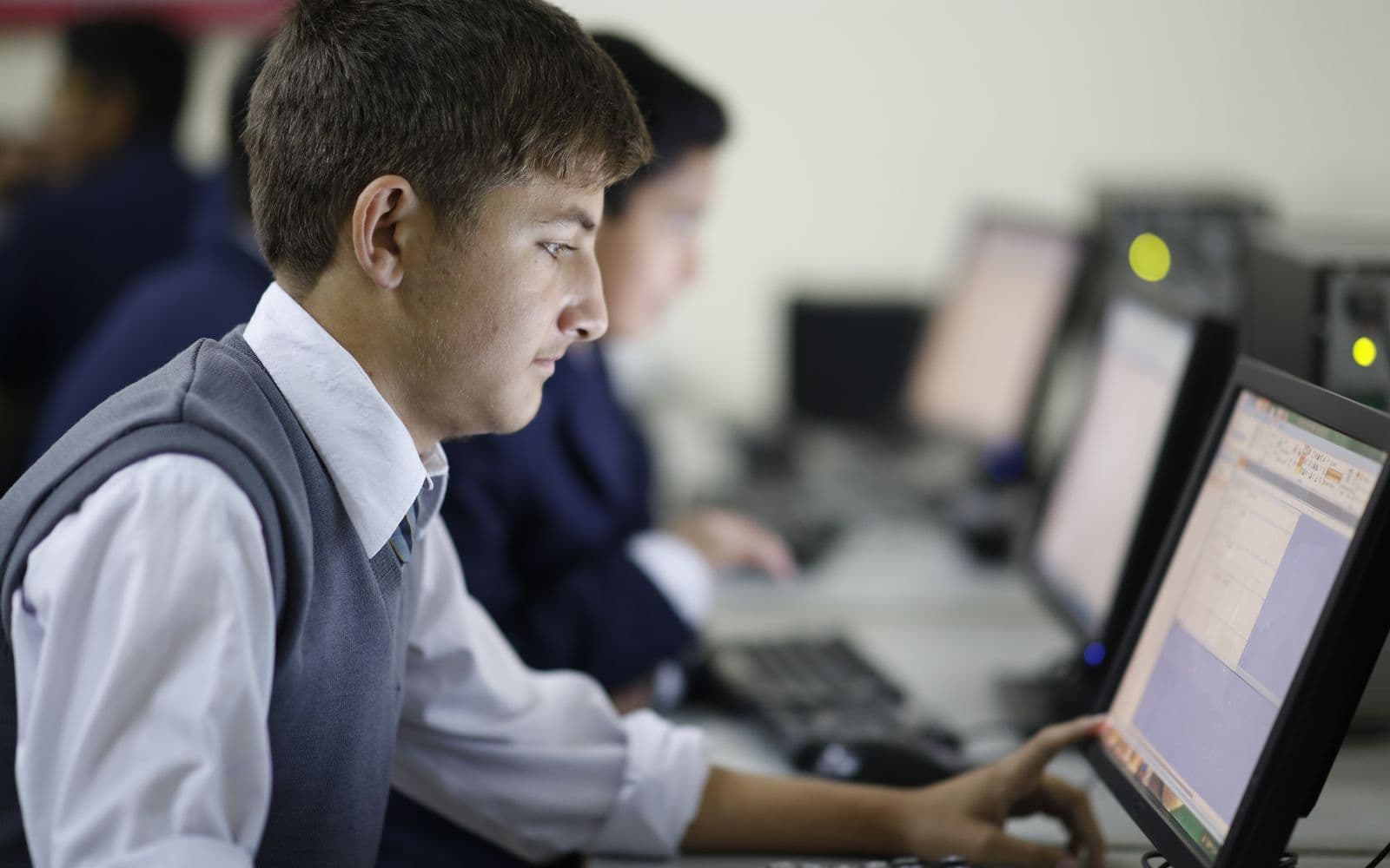 Student in uniform learning on a desktop computer in a computer lab