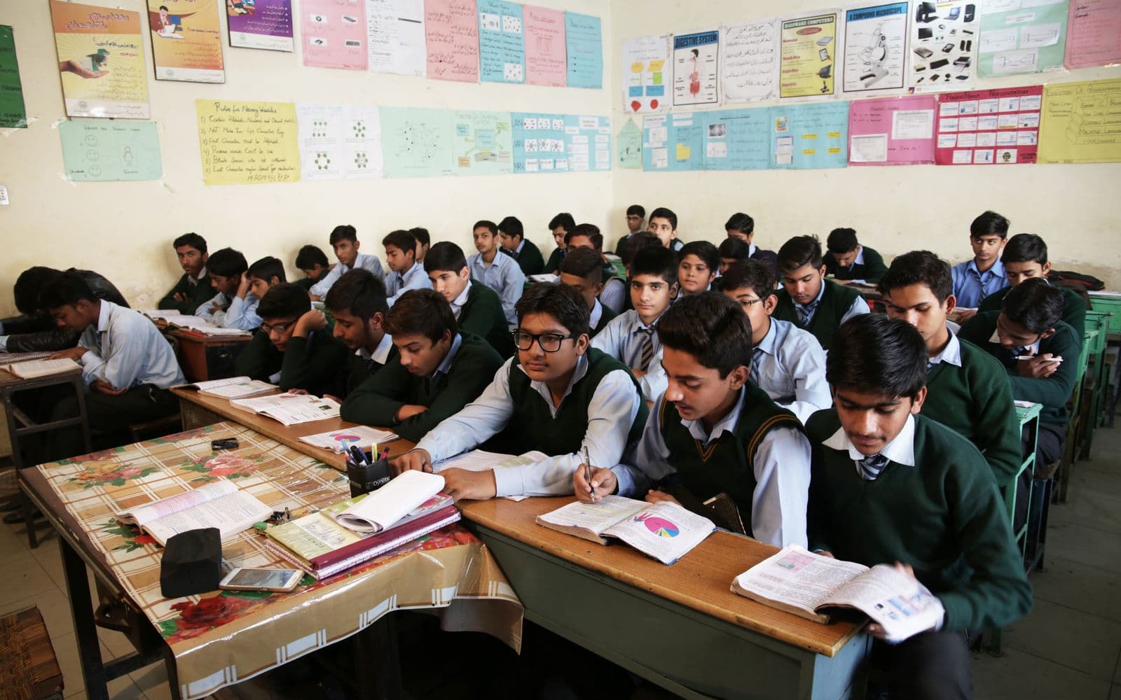 Pakistani secondary-school students studying with textbooks in a classroom
